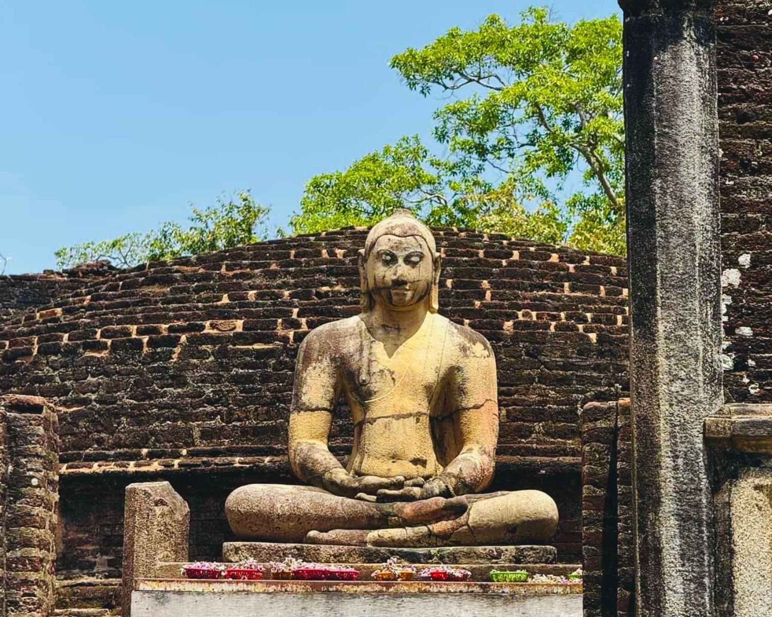 Front close up of seated Buddha at Vatadage in dhyana mudra before tiered brick stupa