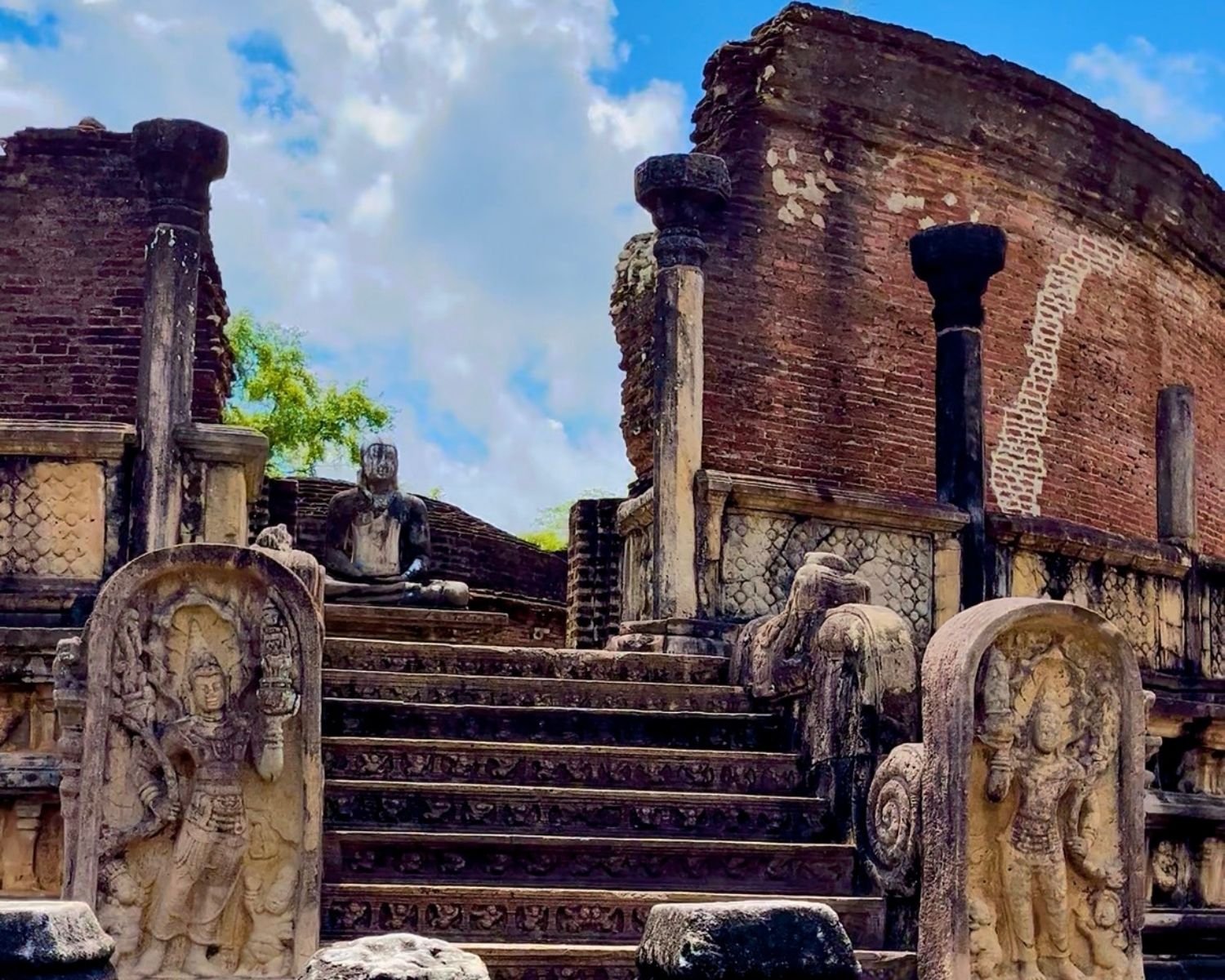 Close view of Vatadage with carved guard stones, ornate steps, stone columns, and seated Buddha