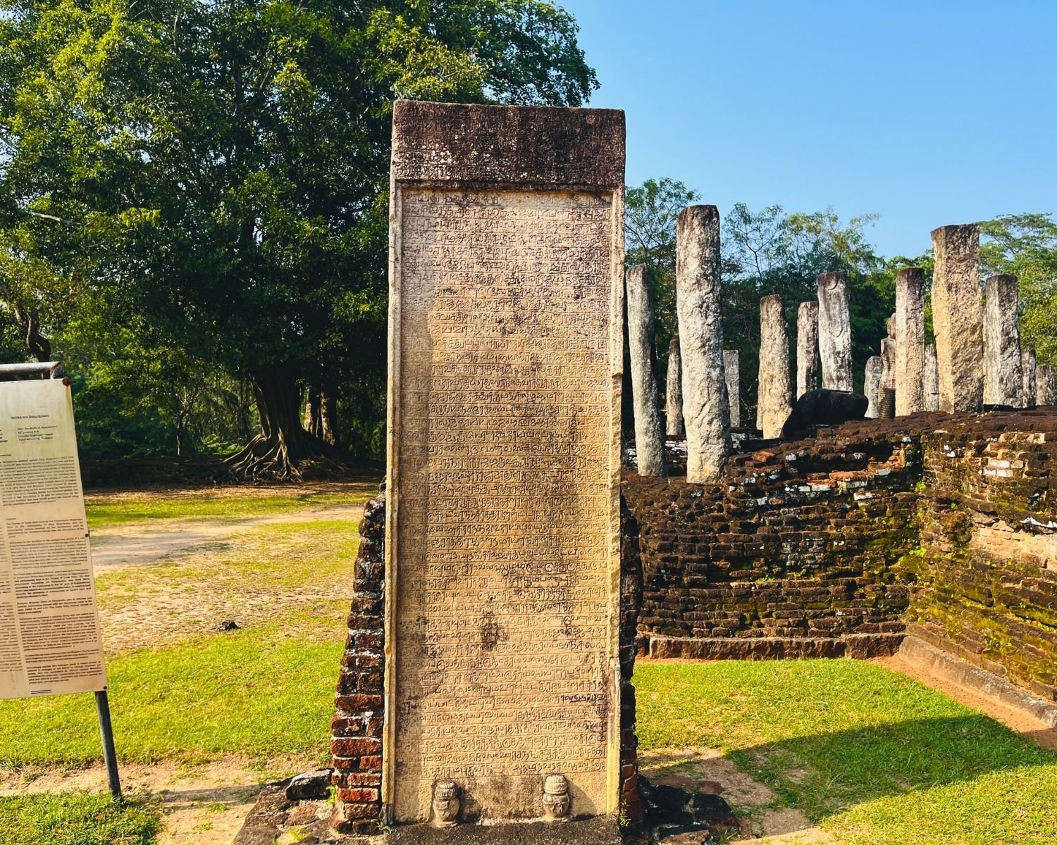 Velikkara Tamil inscription slab at Atadage with Tamil script, brick base, and stone pillars behind