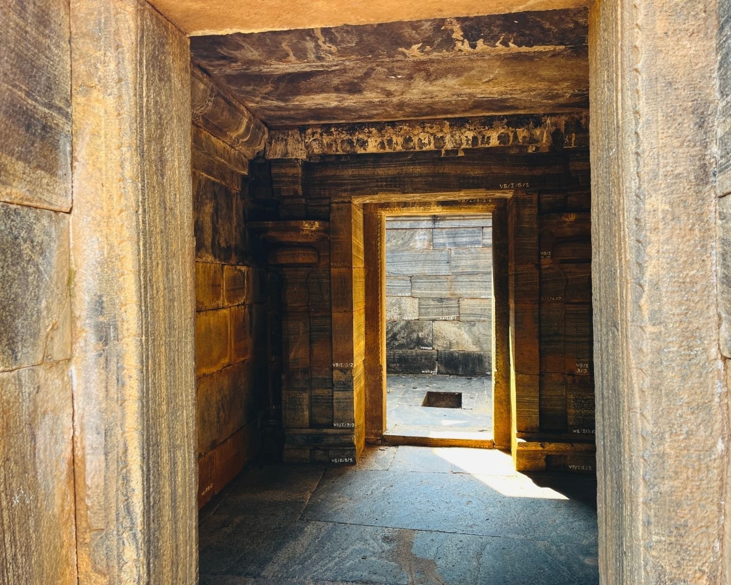 Inside corridor of Shiva Devalaya No.1 with stone walls, carved ceiling, and doorway framing sanctum