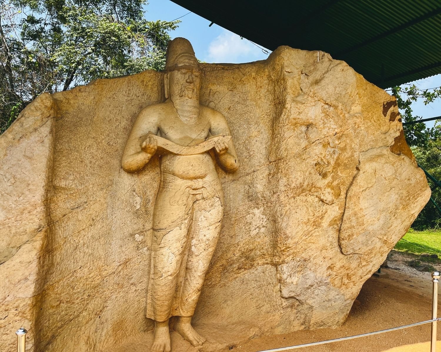 Angled view of statue traditionally identified as King Parakramabahu I carved into large rock face