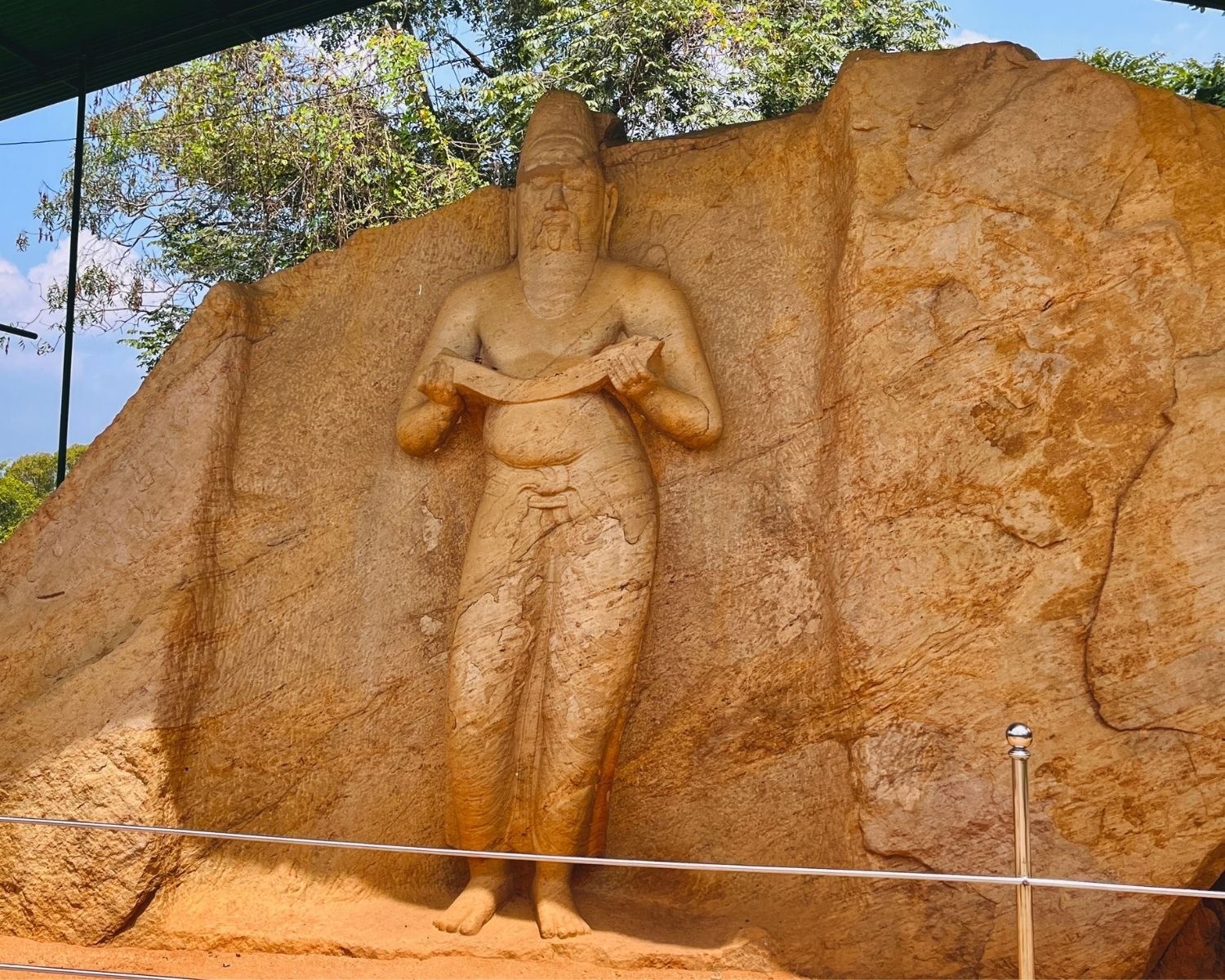 Front view of statue traditionally identified as King Parakramabahu I, rock-carved figure holding ola leaf manuscript