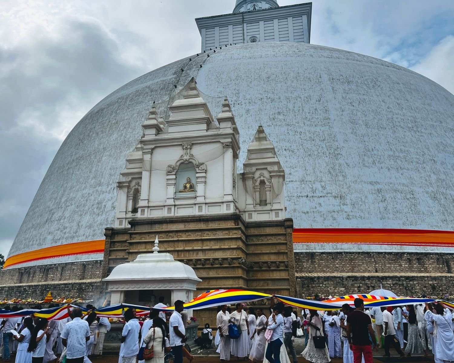 Devotees carry Buddhist flag in offering ceremony around Ruwanwelisaya stupa with incense and flowers