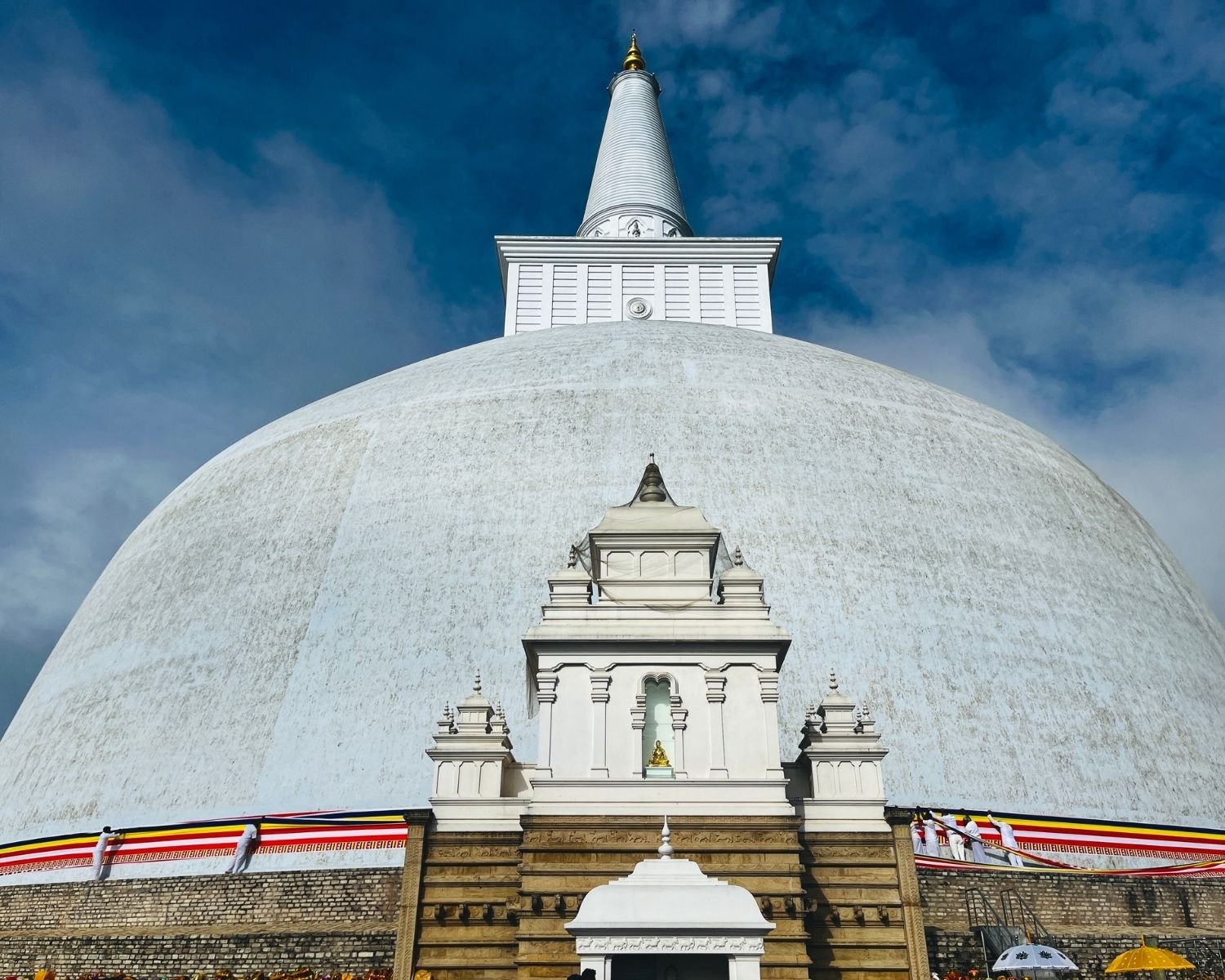 Devotees wrapping Buddhist flag around Ruwanwelisaya stupa at East Vahalkada during offering ceremony