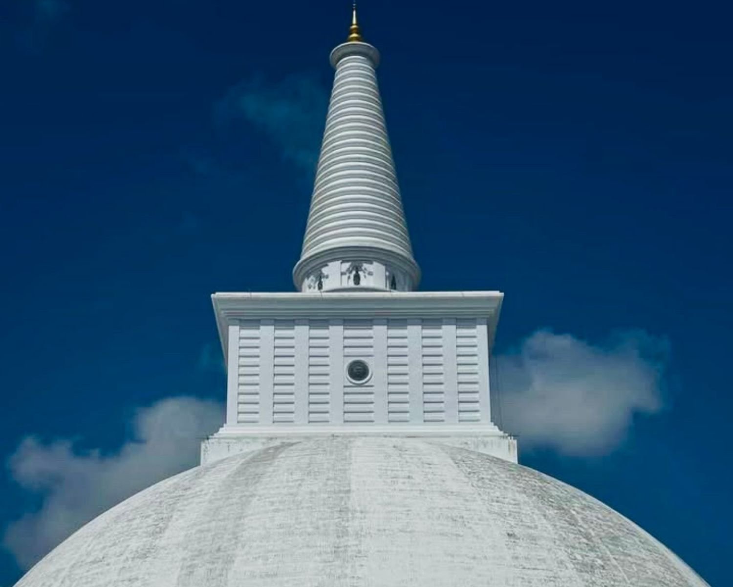 Close view of Sandahiru Seya white harmika, tapering spire, and golden kotha finial against blue sky in Anuradhapura