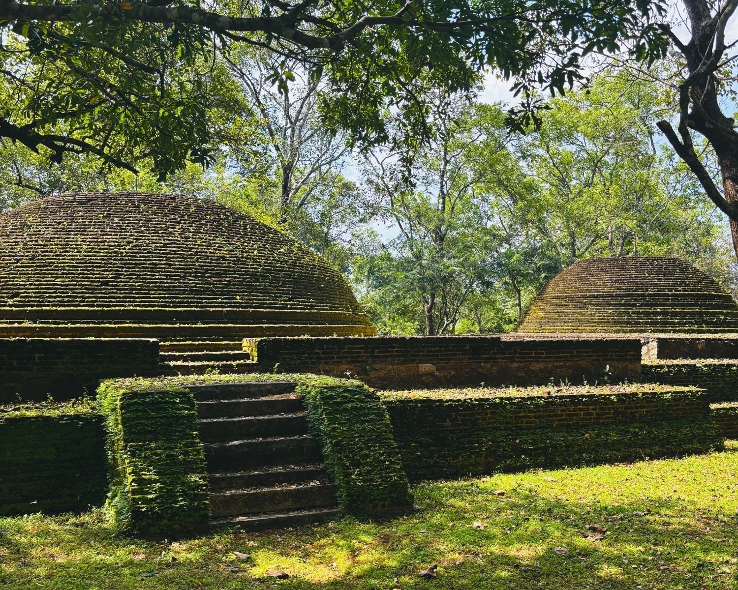 Two moss-covered brick burial stupas with stone steps and platforms south of Lankatilaka Image House