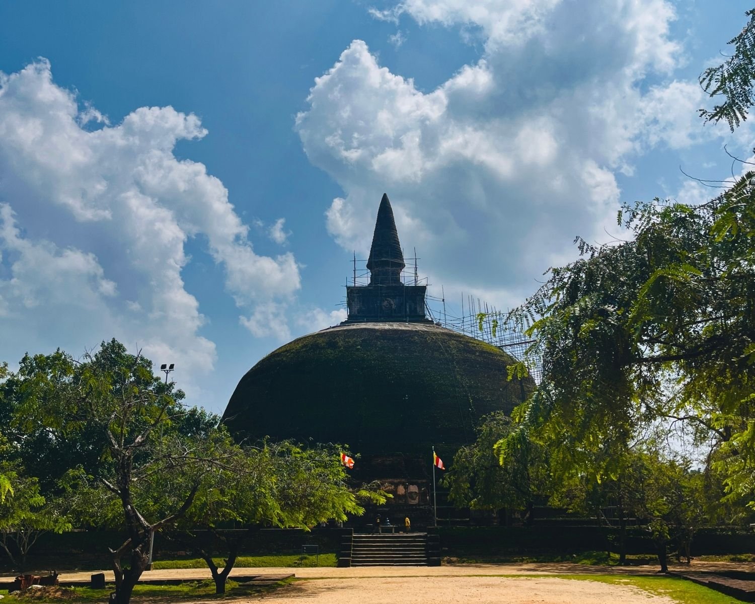 Rankoth Vehera stupa with spire under scaffolding, brick dome, and steps surrounded by trees