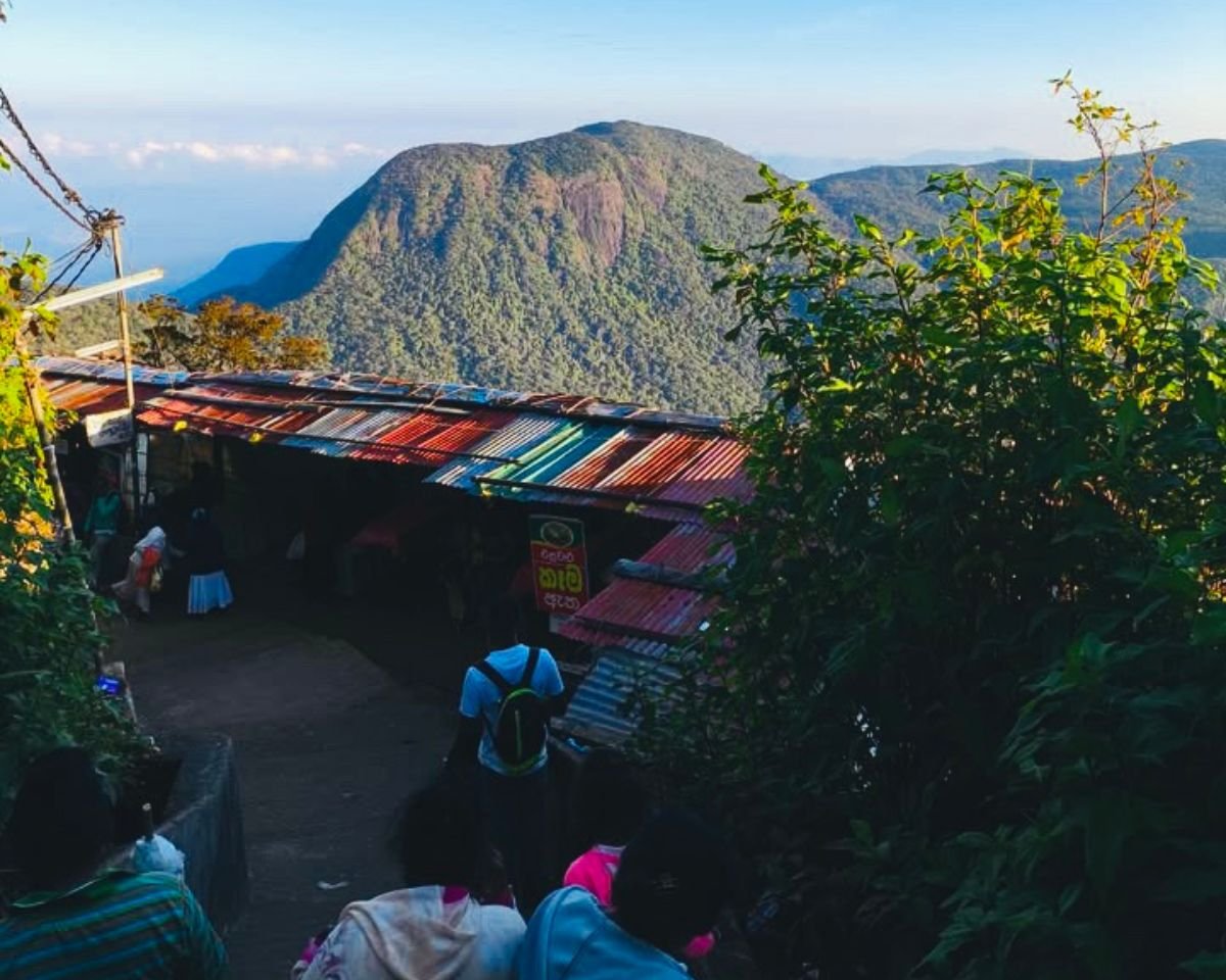 Morning on Adams Peak Hatton trail with pilgrims at colorful tea stalls and Baana(bena) Samanala mountain in Peak Wilderness under clear blue sky
