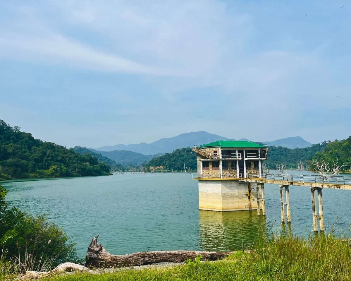 Sluice tower surrounded by calm water and forested hills