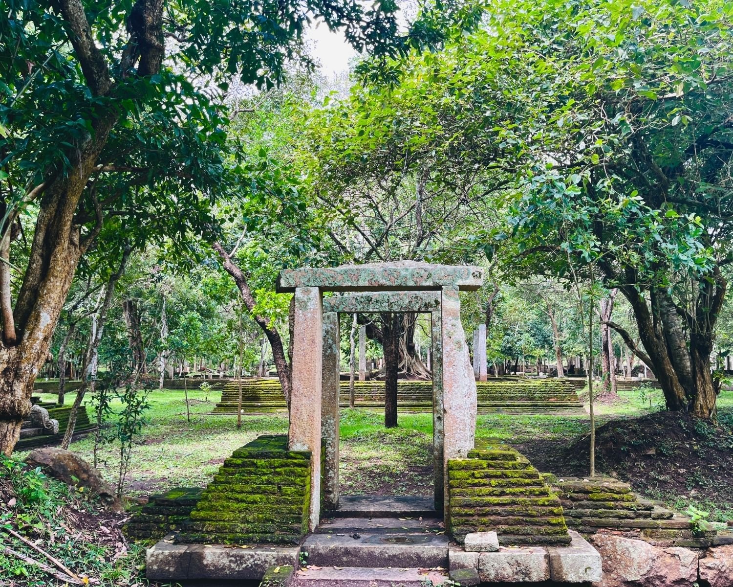 Moss-covered stone doorway at the east entrance frames the raised platform of Abhayagiri Banyan Tree Shrine in Anuradhapura