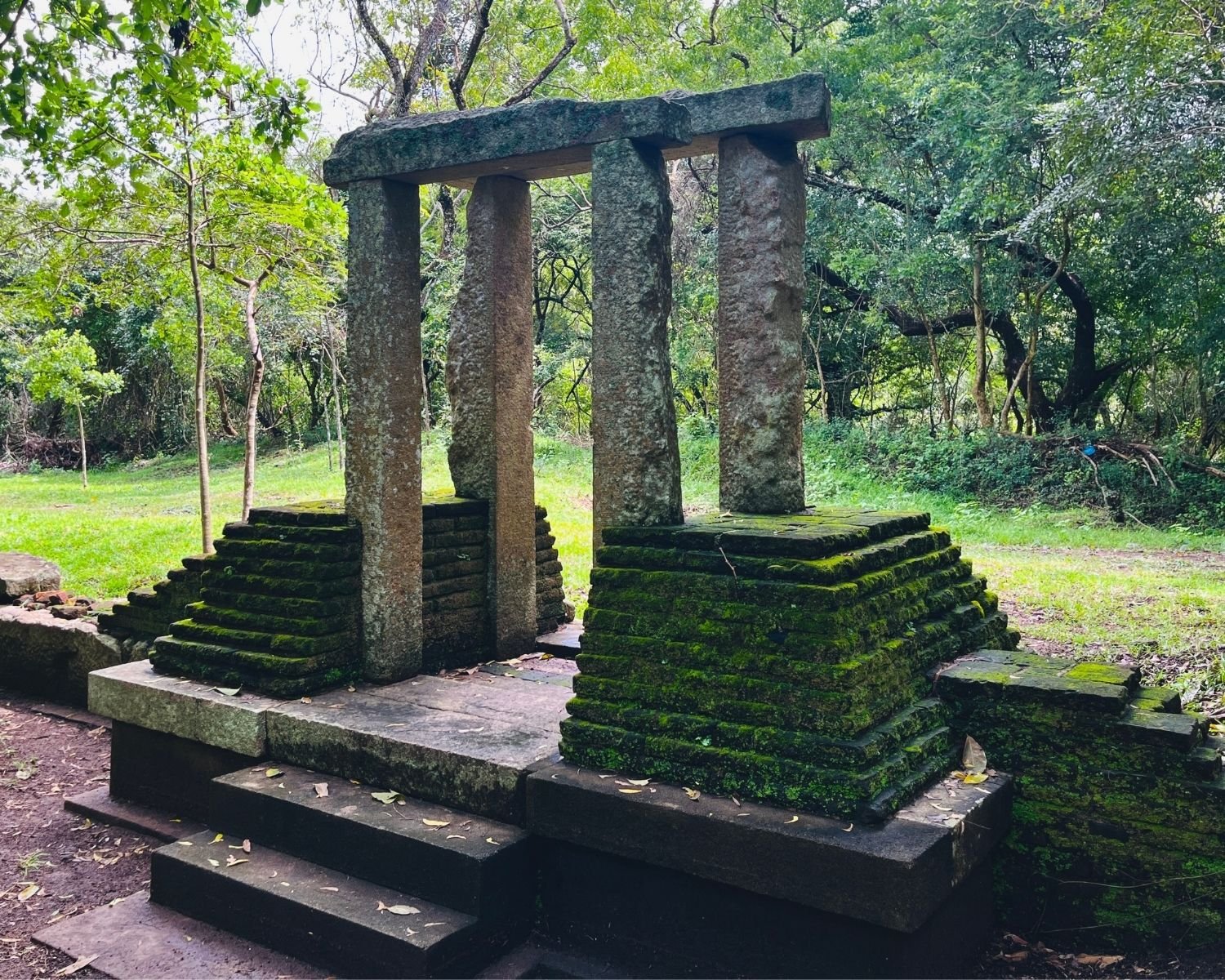 Side view of moss-covered east stone doorway with stepped wing walls at Abhayagiri Banyan Tree Shrine in Anuradhapura