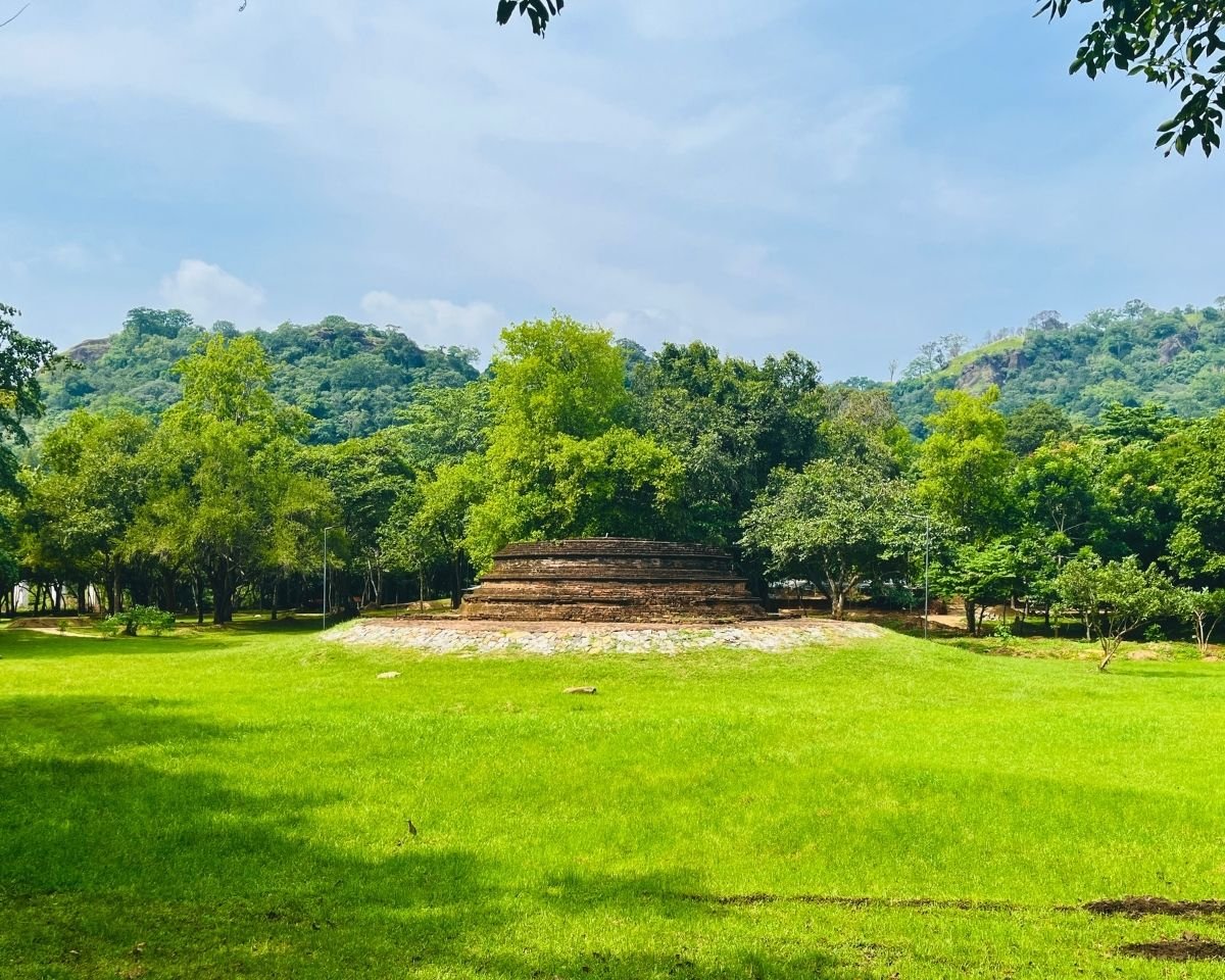 Ruined brick stupa surrounded by forested hills at Buduruwagala