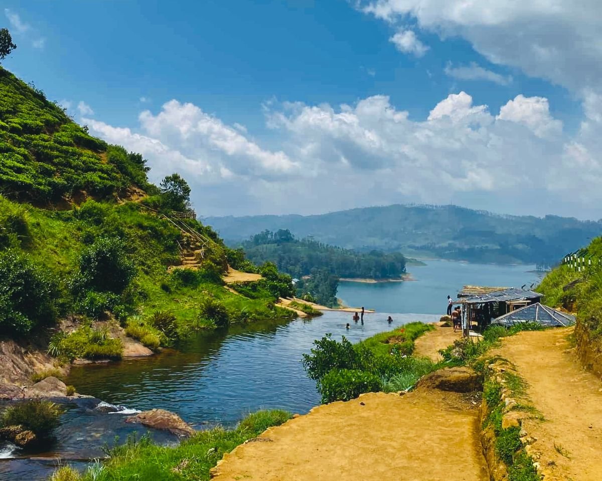 Maussakelle Reservoir viewpoint from Hatton Maskeliya road with blue water tea estates power lines and Maskeliya town on the shore below misty mountains