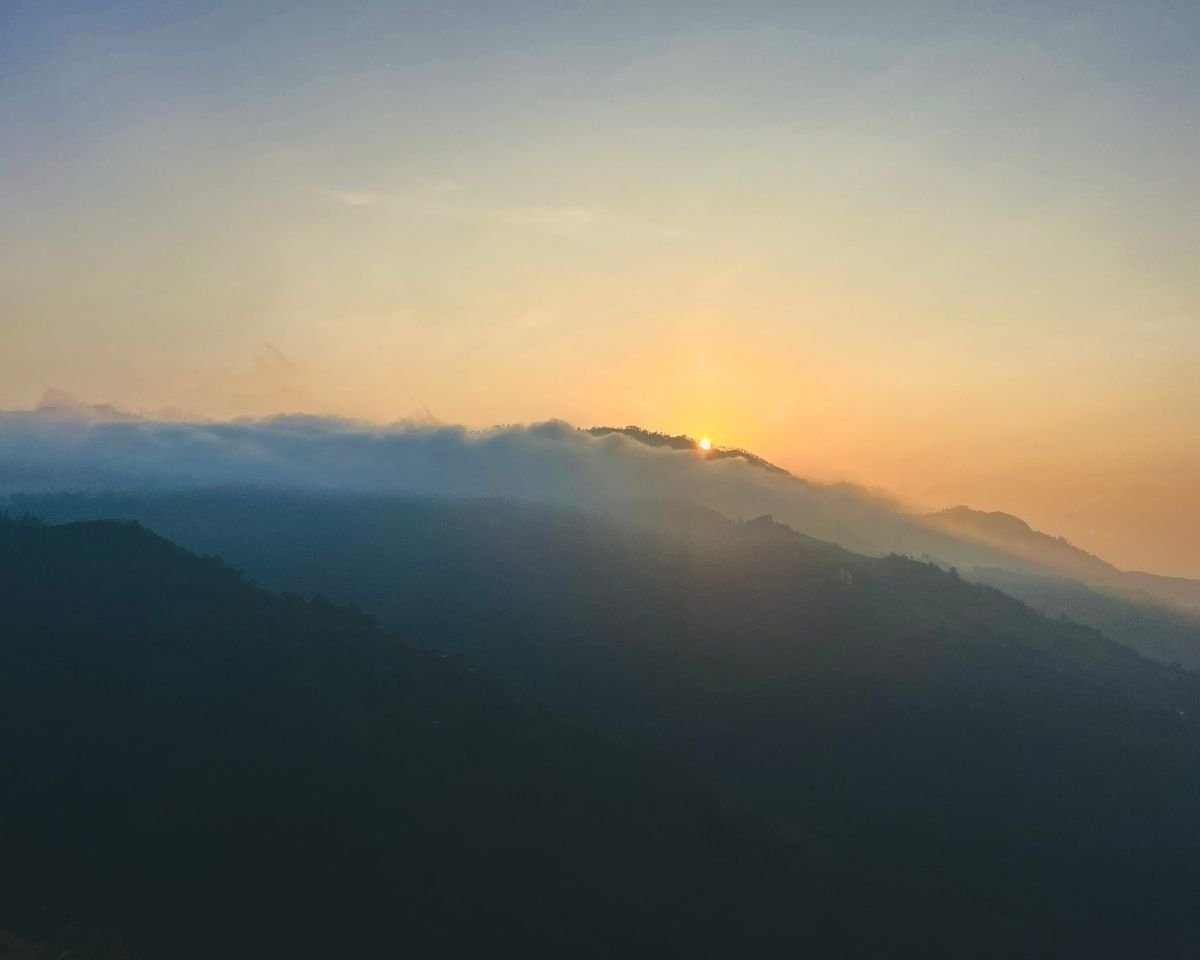 Sunrise above cloud-covered mountain ridges