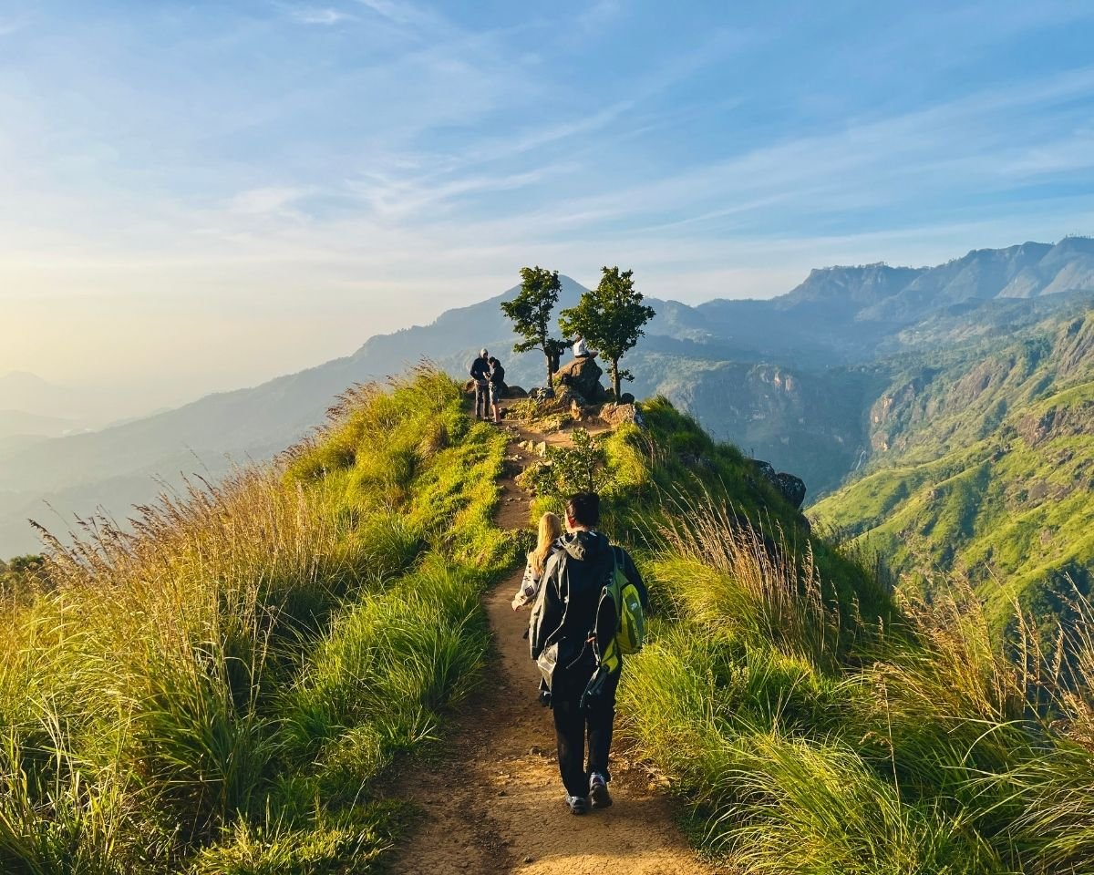 Hikers walking along a grassy ridgeline trail