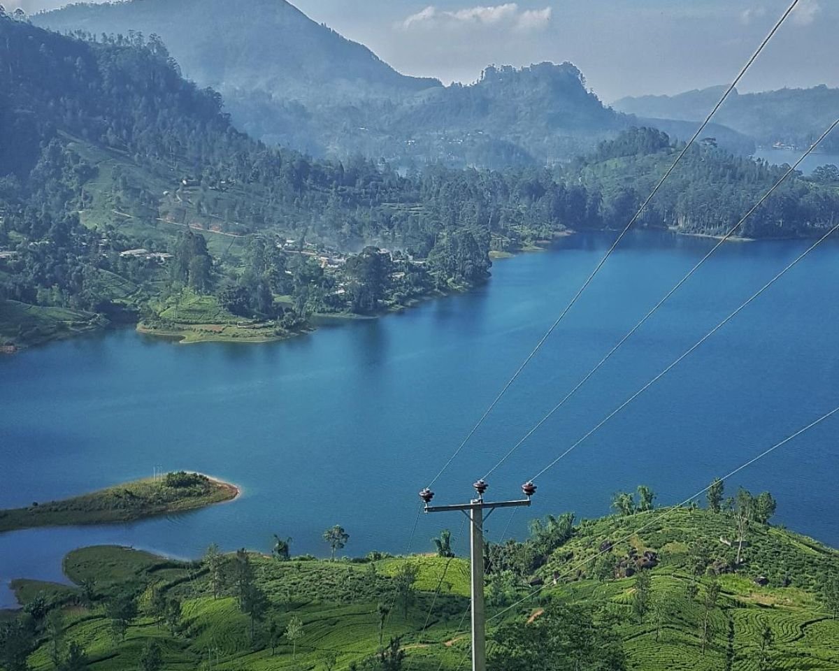 Castlereigh Reservoir viewpoint from Hatton Maskeliya road with blue water tea estates power lines and Maskeliya town below misty mountains in Sri Lanka hill country