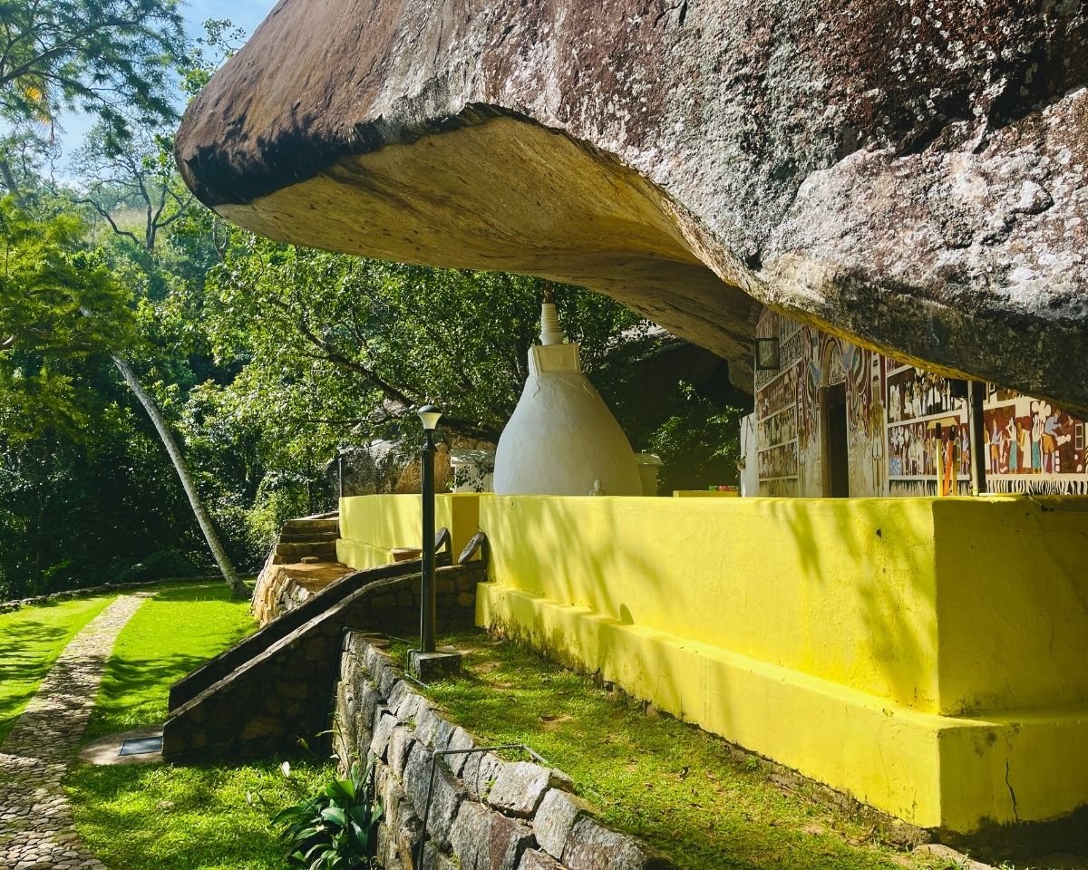 White stupa beside a cave shrine beneath the cliff