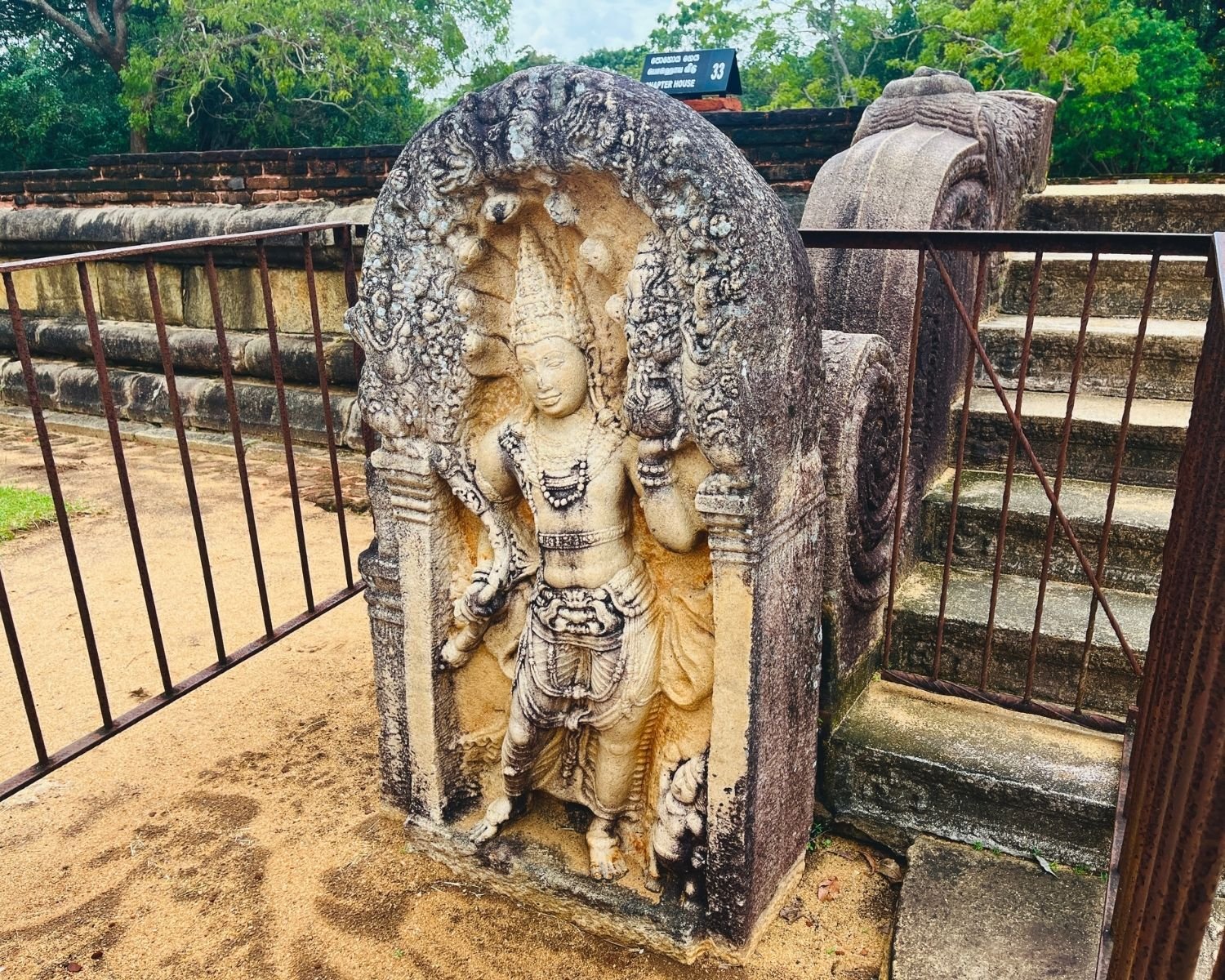 Rathna Prasadaya guardstone at Abhayagiri, the most beautiful and detailed guardstone found in Sri Lanka, 10th-century carving of crowned Nagaraja deity under seven-hooded cobra canopy with intricate jewelry, ritual pot and lotus, lichen-covered stone