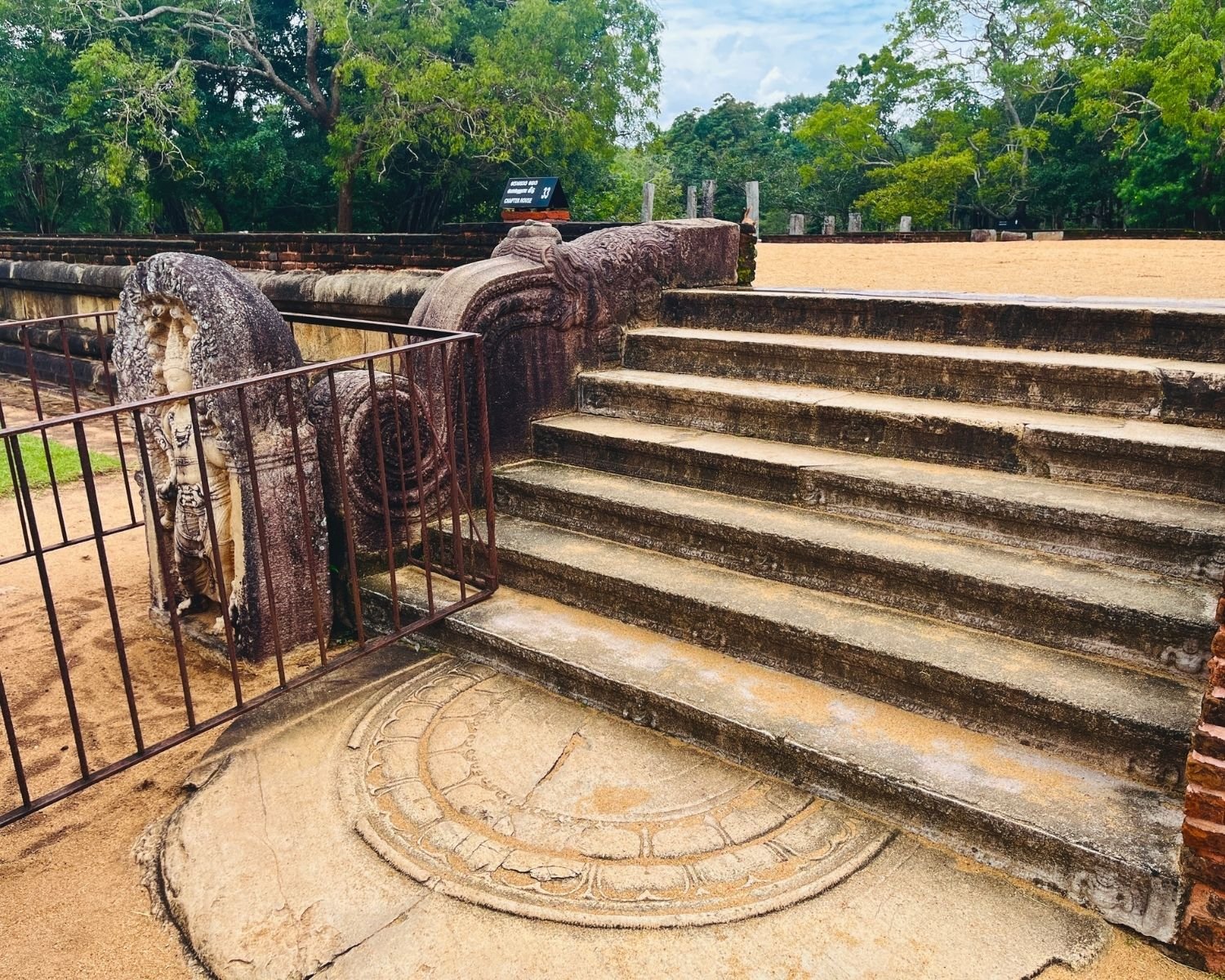 Rathna Prasadaya Chapter House staircase at Abhayagiri showing complete 7th–9th century ensemble: Nagaraja guardstone muragala, makara dragon korawakgala balustrade, and sandakada pahana moonstone at foot of steps, Sri Lanka’s finest stone carvings