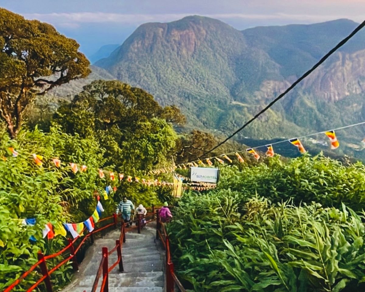 Sri Pada Adam's Peak trail with red railings prayer flags and pilgrims climbing steps with Peak Wilderness mountains in background near Hatton Sri Lanka