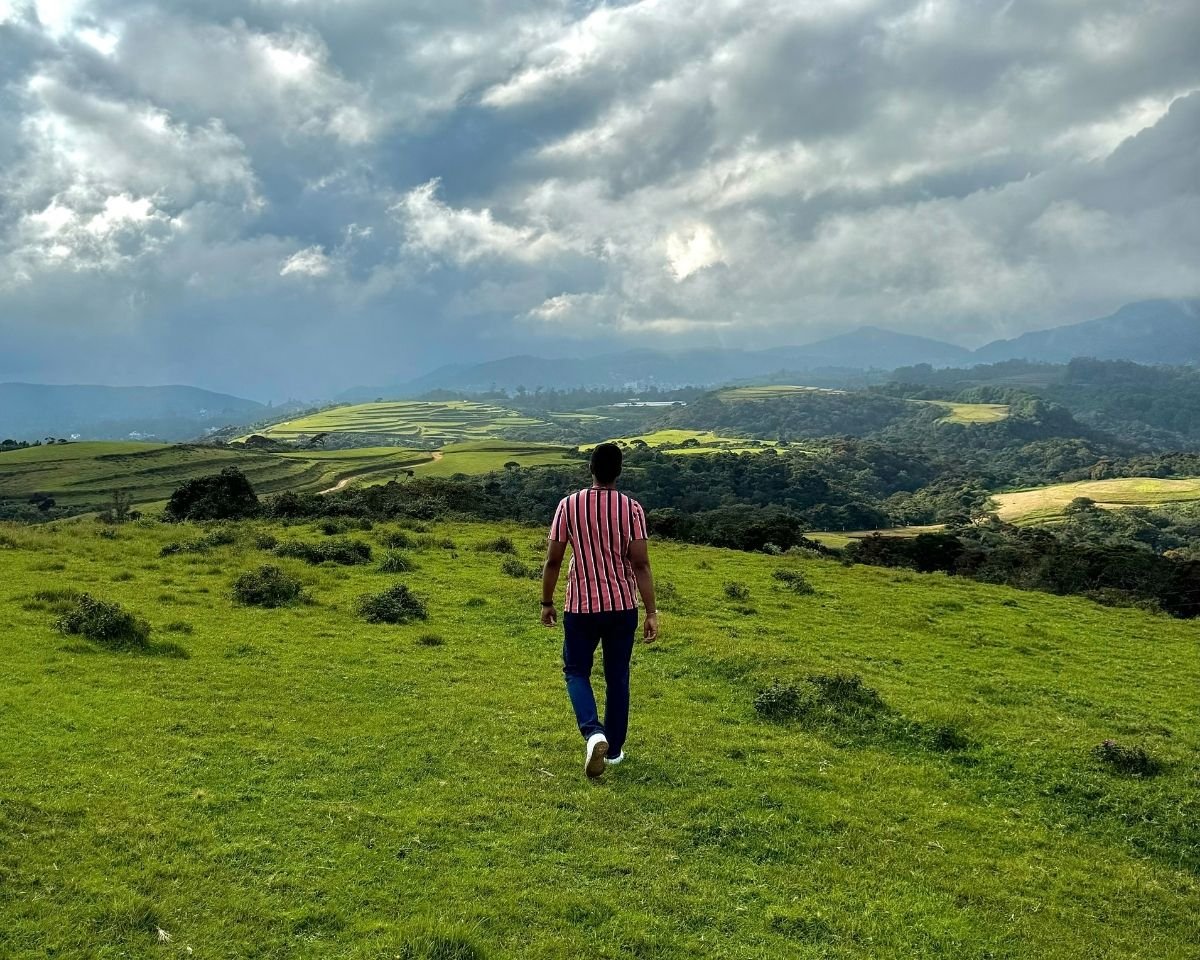 Expansive green rolling plains and hills with terraced farms at Moon Plains, Nuwara Eliya, Sri Lanka under cloudy sky