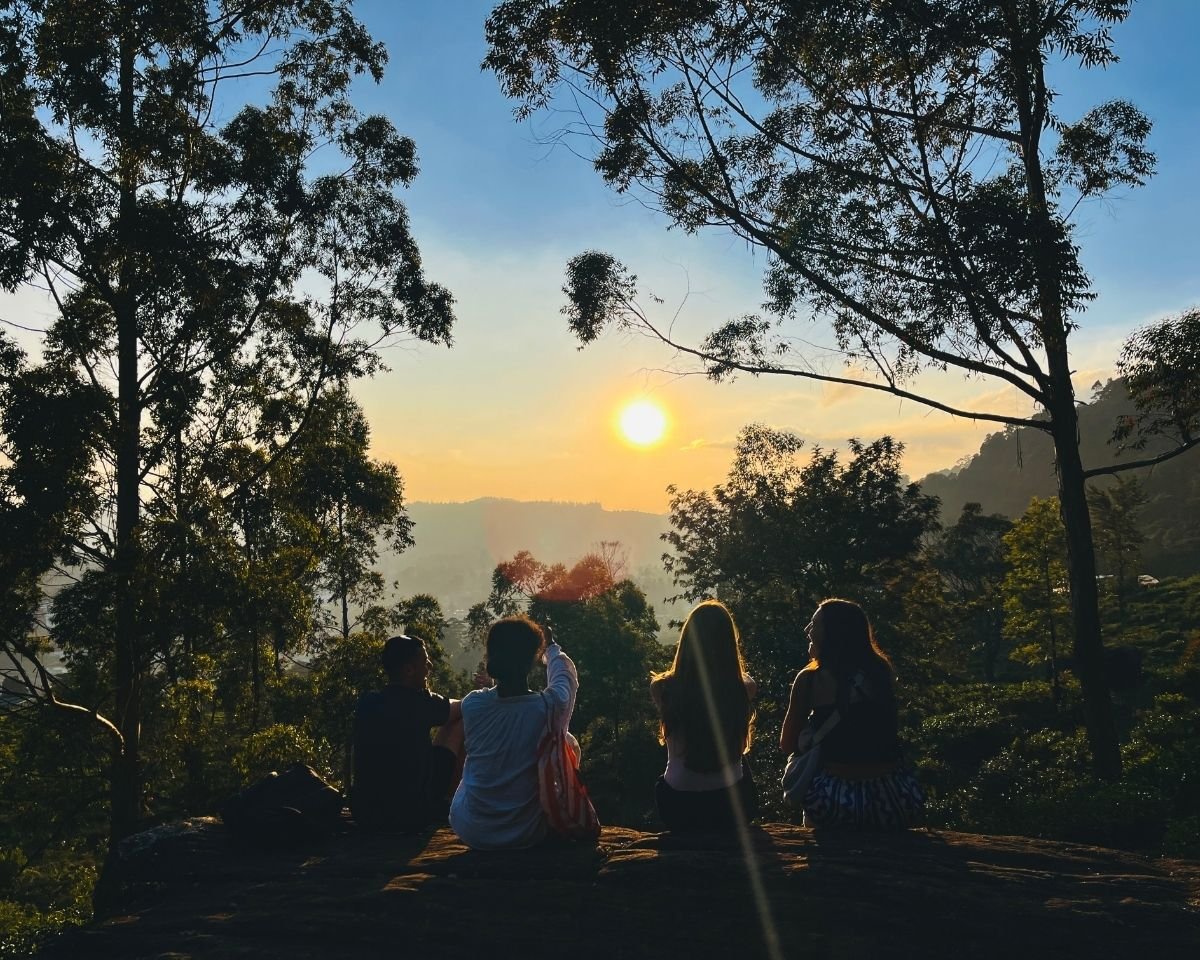 Group of people watching sunset from Sunset Rock viewpoint near Lovers Leap Falls with tea estates and mountains Nuwara Eliya