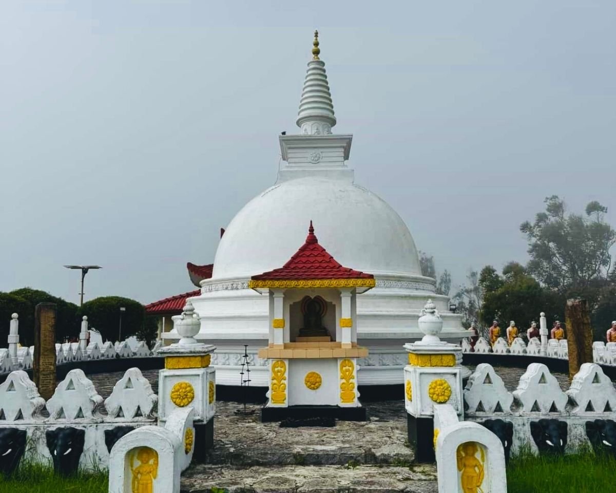 White stupa with red roof shrine and elephant fence at Swarnagiri Maha Viharaya Single Tree Temple Nuwara Eliya Sri Lanka on misty hill